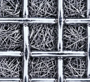Close-up of random metal fibers beneath a square support mesh in sintered fiber felt